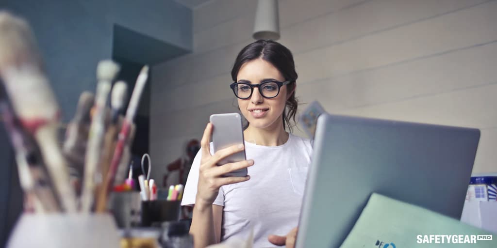 woman holding phone while working wearing glasses