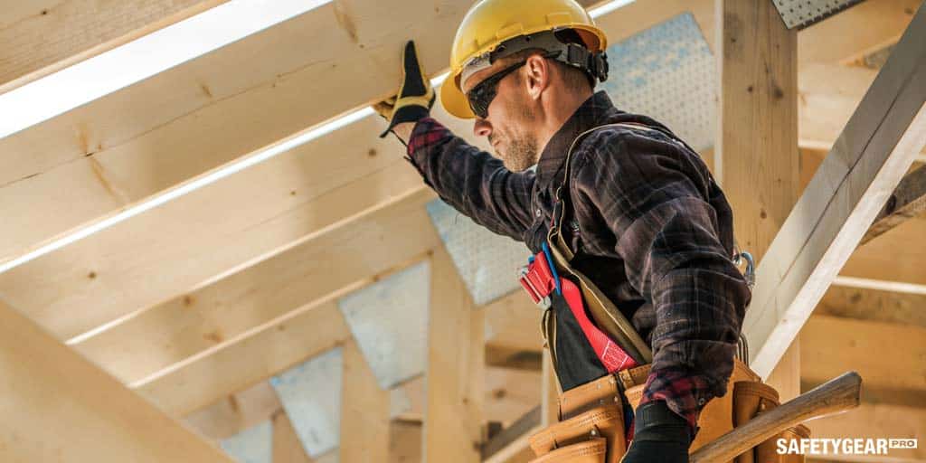 Man wearing hardhat carrying wood