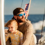 Man and child wearing sports sunglasses on a boat
